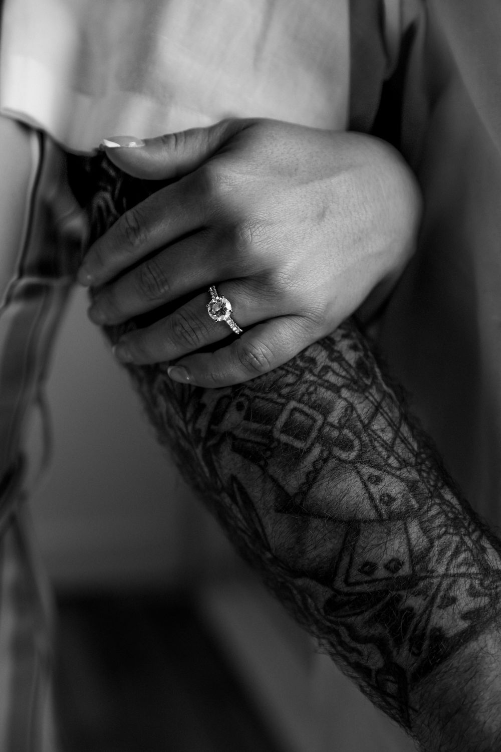 Black and white close-up of detailed tattoo artwork on an arm with ring.