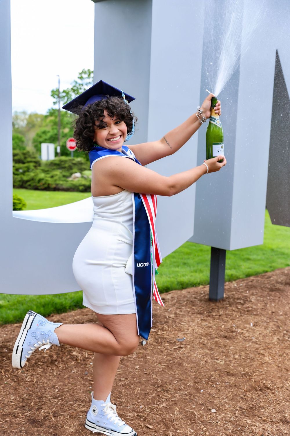 Playful graduation photos showing poses against large outdoor letter decorations.