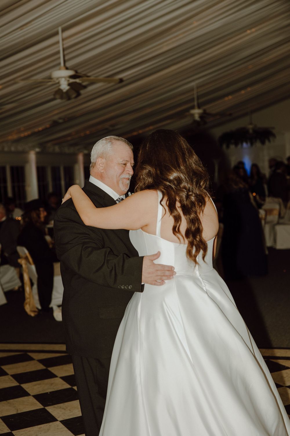 A special dance moment captured on a checkered floor during a wedding reception.