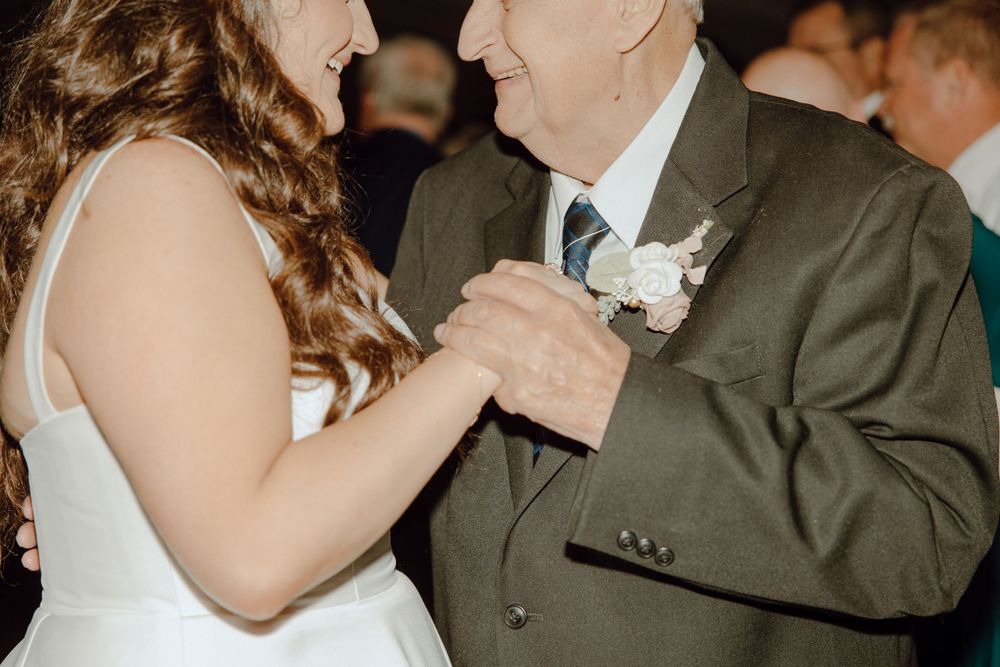 A couple shares a romantic dance at their wedding reception, with the bride in white and groom in dark attire.