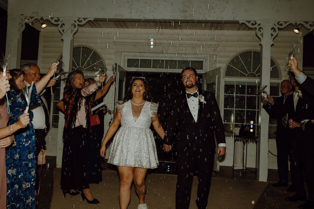 Wedding guests dancing and celebrating on a brightly lit dance floor.