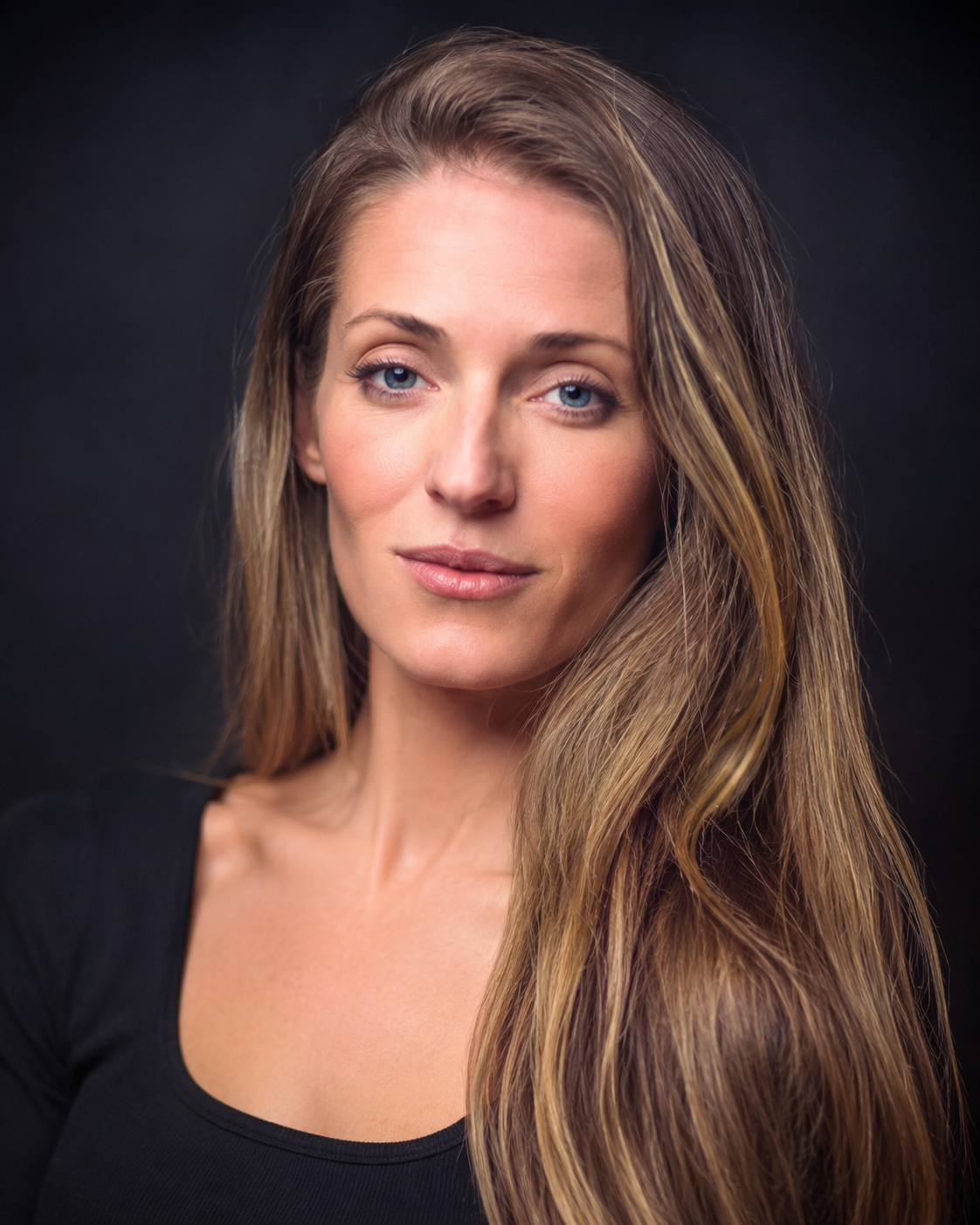 Woman in striped crop top and jeans kneeling before a glowing red heart backdrop in colorful studio lighting.
