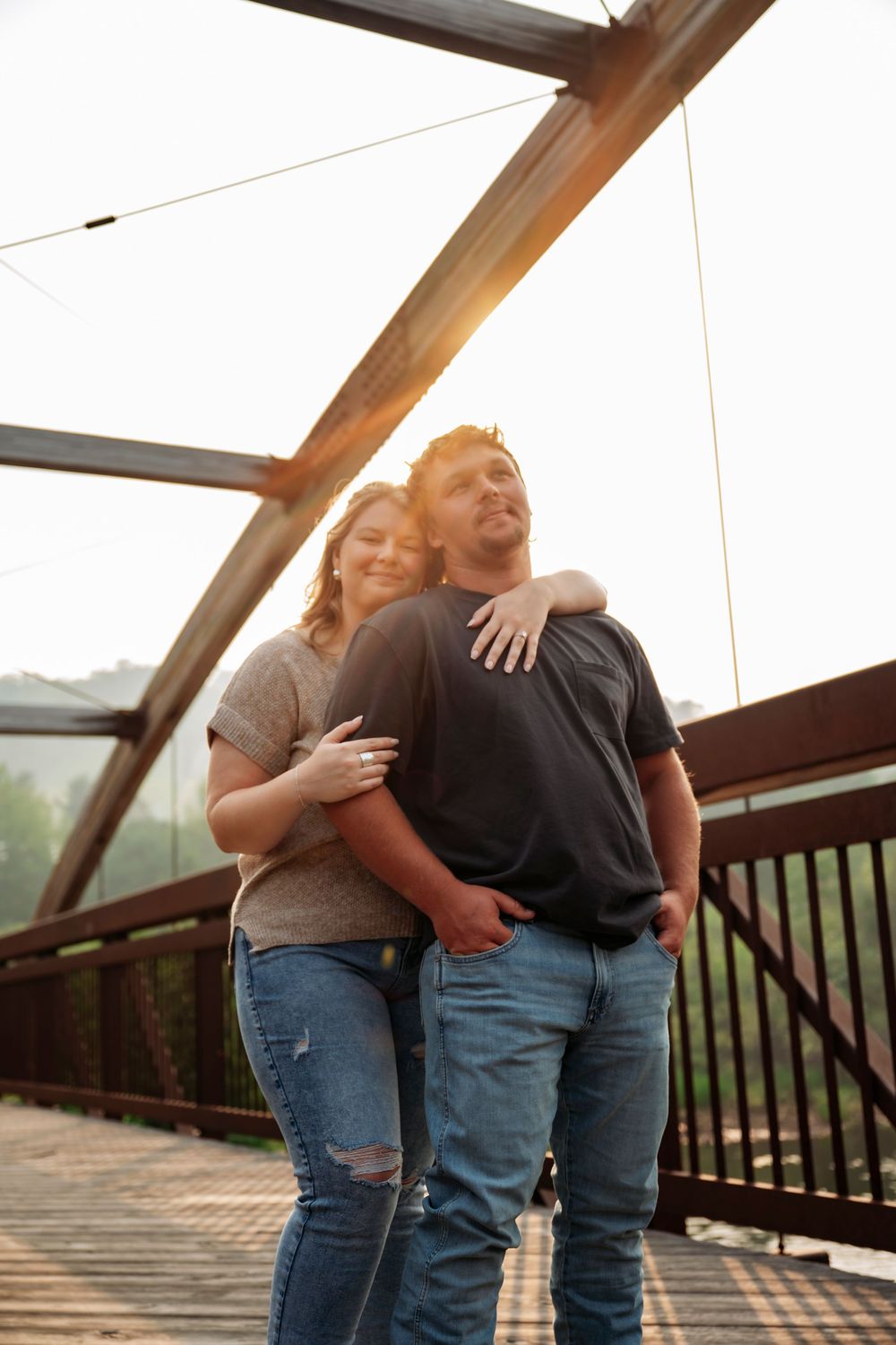 Couple embracing on bridge with sunlight coming through