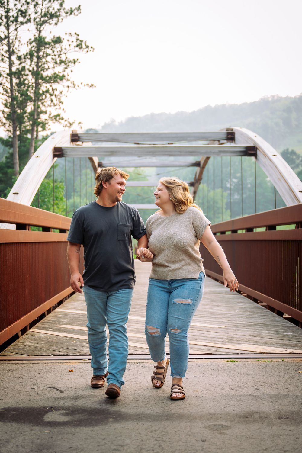 engaged couple walking on bridge looking at each other Giants Ridge, Minnesota