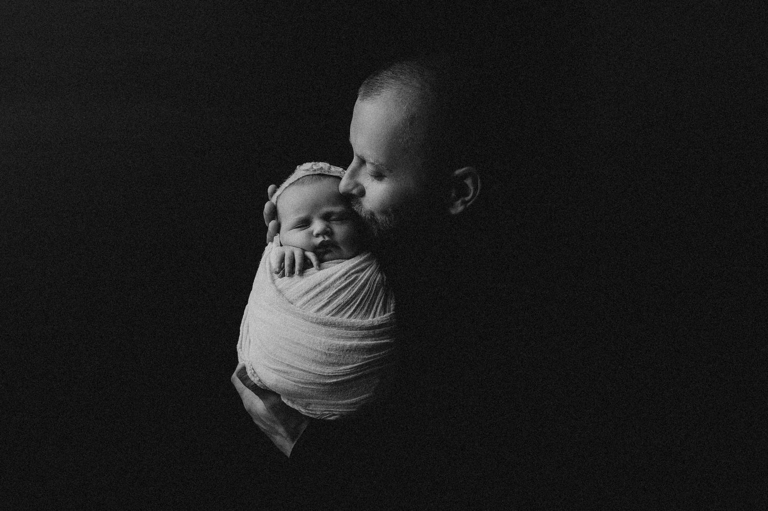The father kissing his newborn baby girl in a cheeck