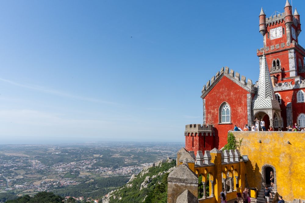 Colorful Pena Palace in Sintra Portugal perched on a hilltop against blue sky.