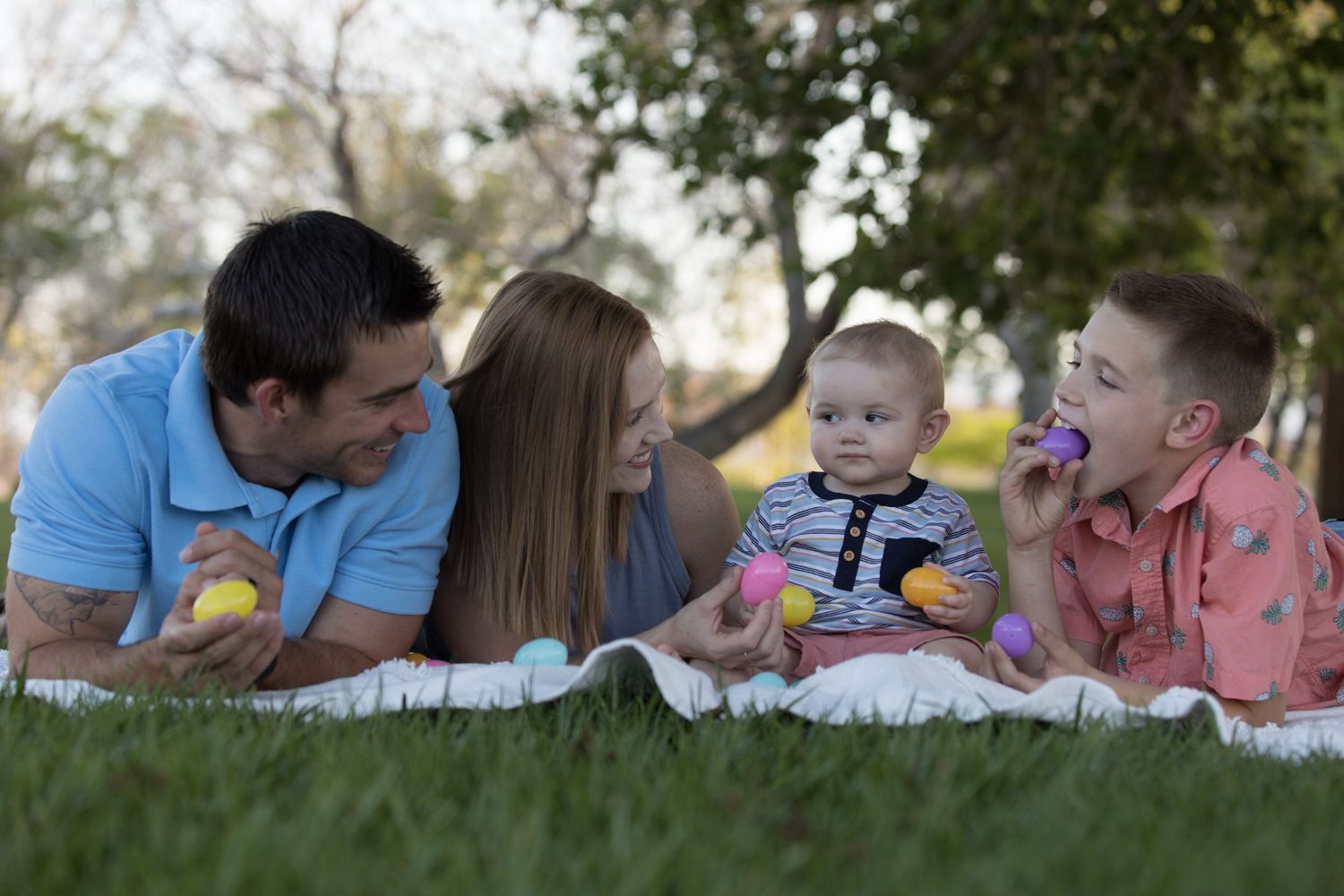 Family members lie on blankets outdoors enjoying a relaxing moment together in nature.