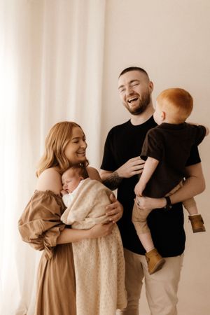 Happy family portrait with two children in neutral colors against white background.