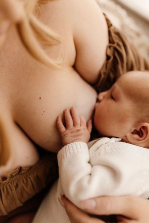 Tender nursing moment between mother and baby in warm, intimate lighting.
