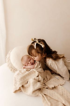 Sweet moment of connection between sleeping infant and caregiver on white bedding.