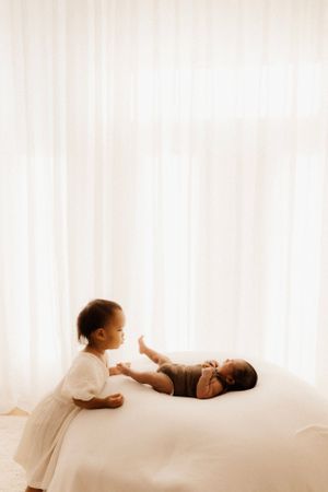 Two children interact on white backdrop during minimalist photo session.