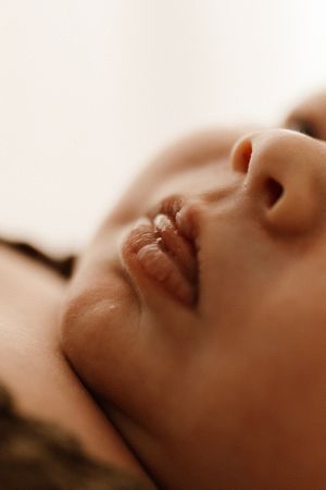 Close up profile of peaceful sleeping newborn with soft lighting and warm tones.
