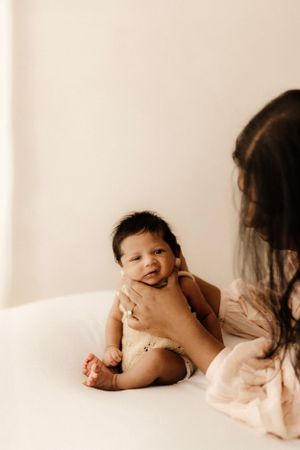 An intimate moment of a parent and baby sitting together against a white background.