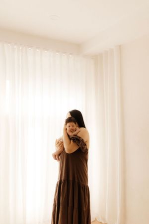 A gentle embrace captured in warm tones against flowing white curtains.