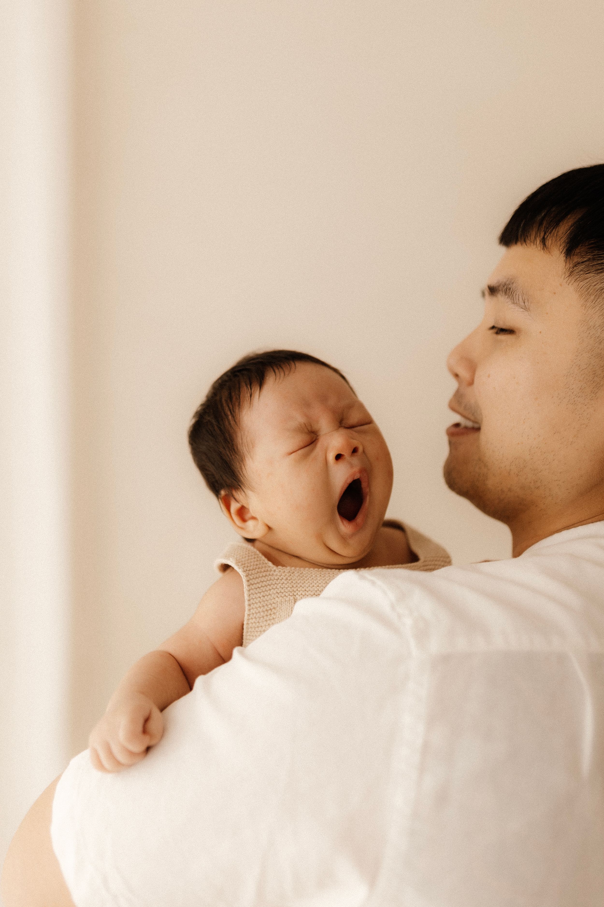 A joyful moment between parent and baby as the little one yawns widely.