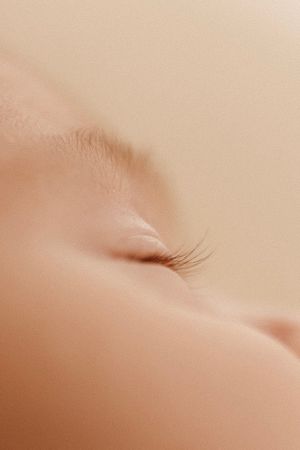 Extreme close-up of eyelashes and skin in soft beige tones.