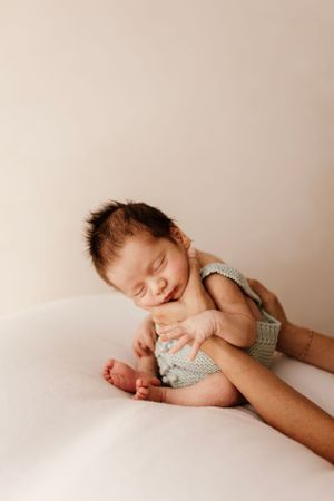 Peaceful sleeping newborn in grey knit outfit laying on white surface.