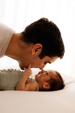 Intimate bonding moment between parent and infant on white surface.