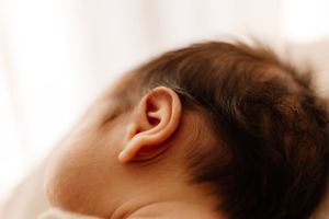 Close-up macro shot of newborn baby's ear against soft background.