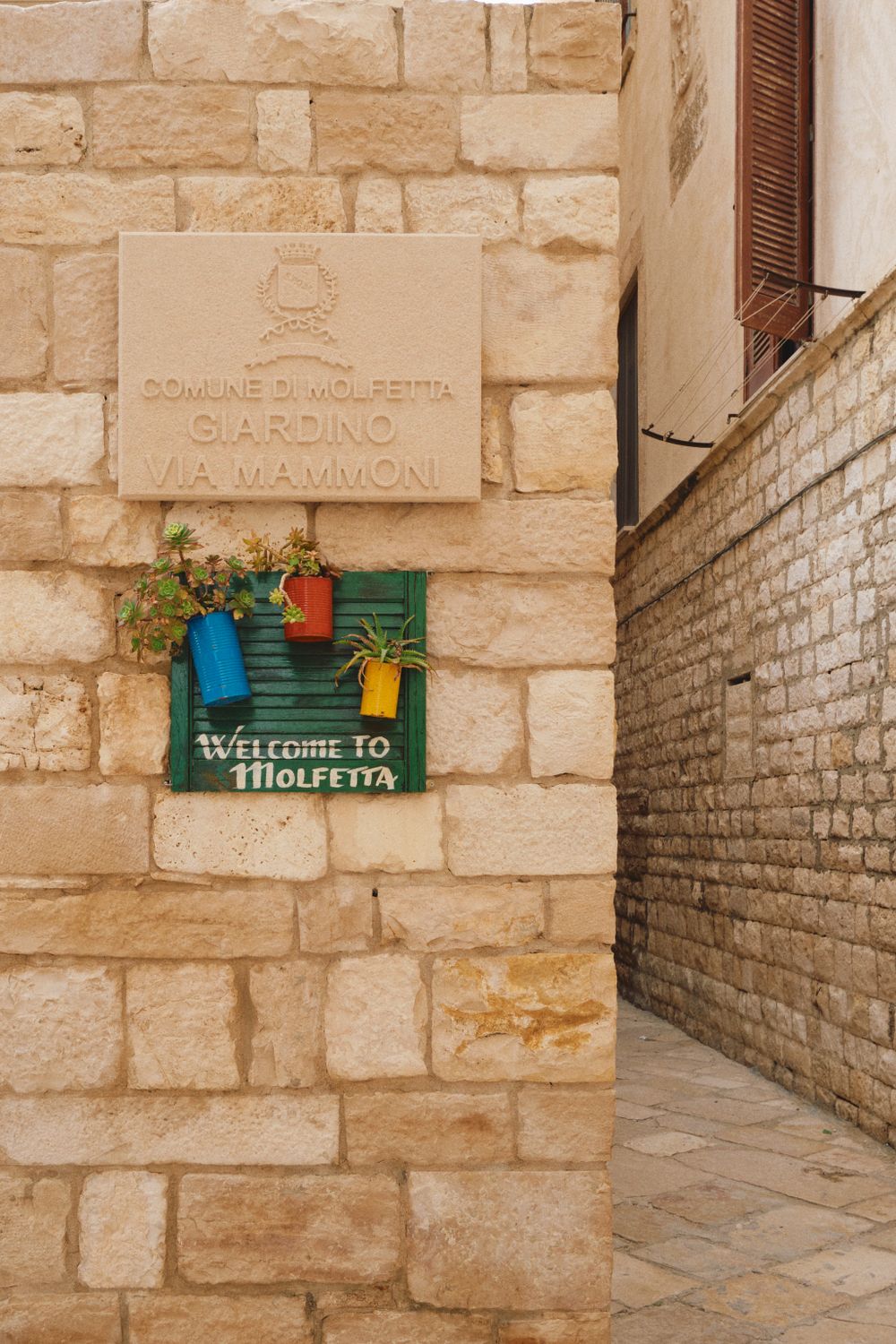 A stone wall with colorful decorative signs and plaques in Italian.