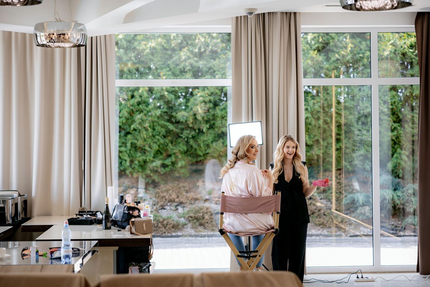 A bright contemporary room with large windows where wedding preparations are taking place.