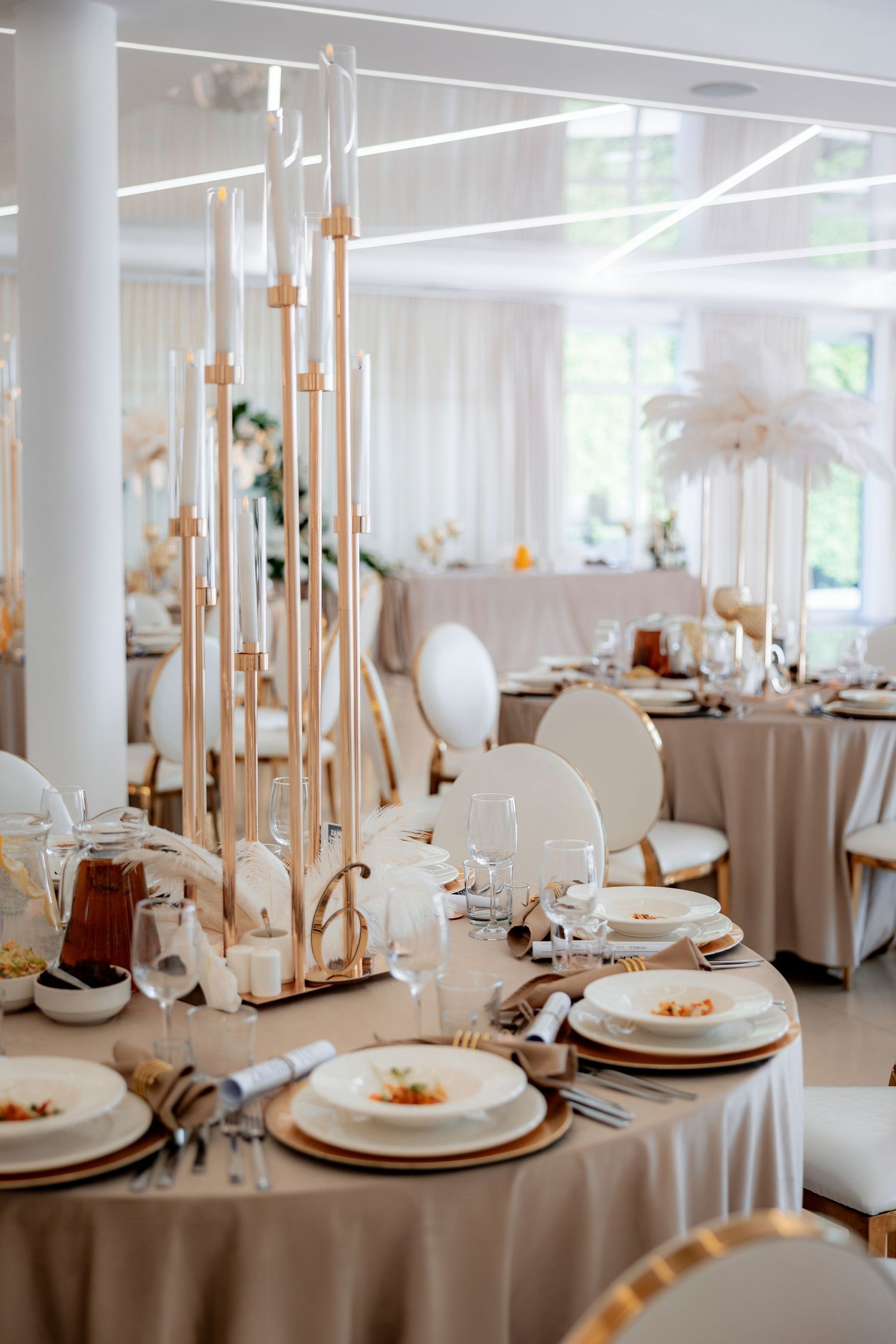 Elegant wedding reception table with tall gold candle holders and white place settings.