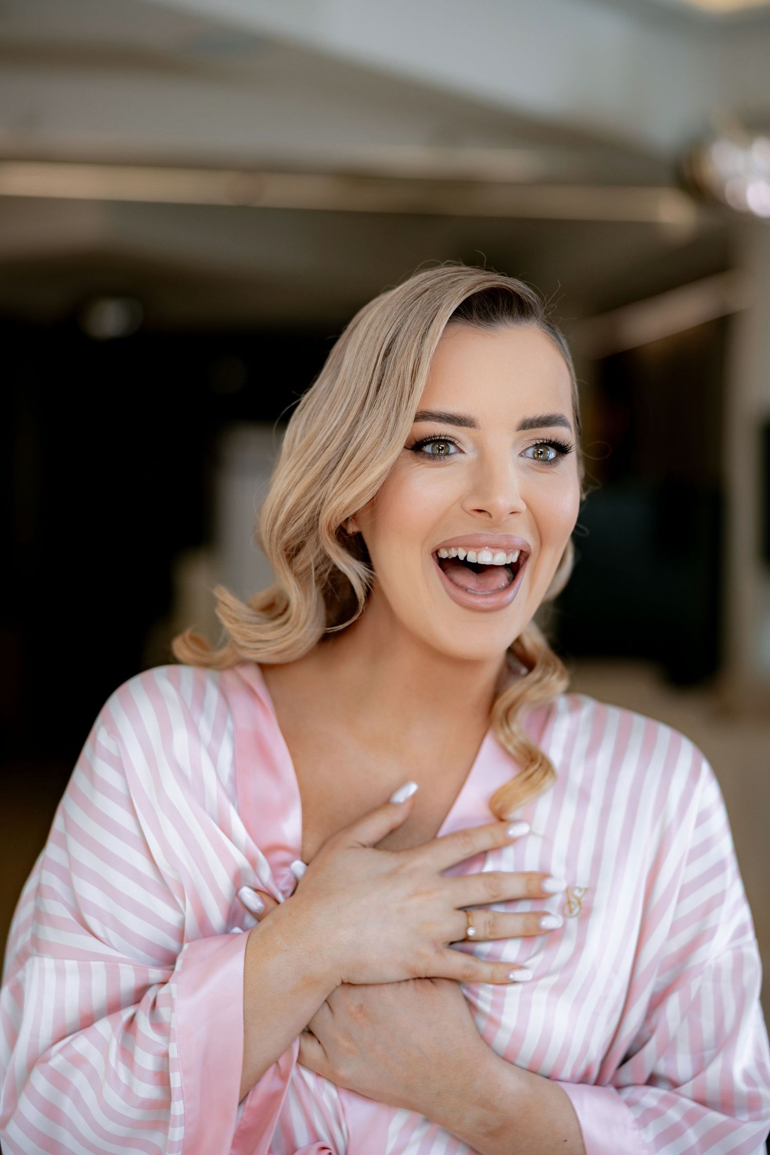 A joyful moment captured during wedding day preparations in a pink striped robe.