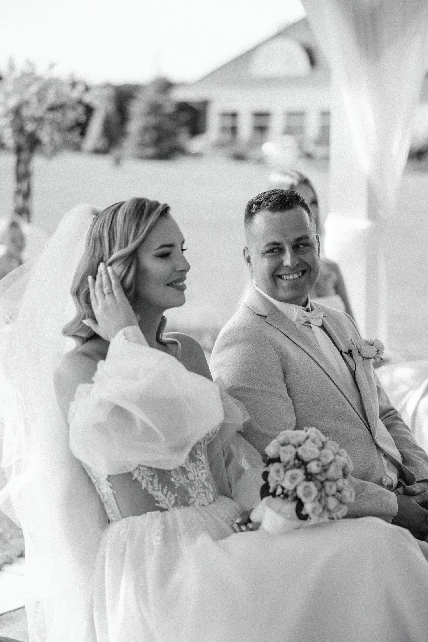 Black and white wedding portrait under white gazebo during outdoor ceremony.