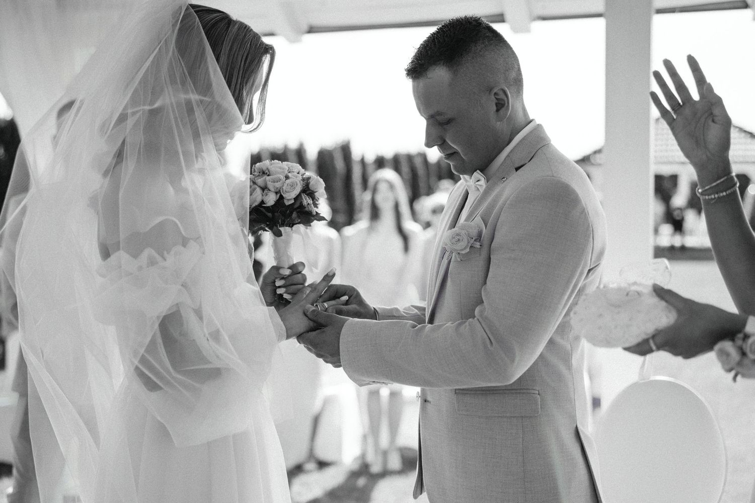 Beautiful black and white photo capturing an intimate ring exchange moment during a wedding ceremony.