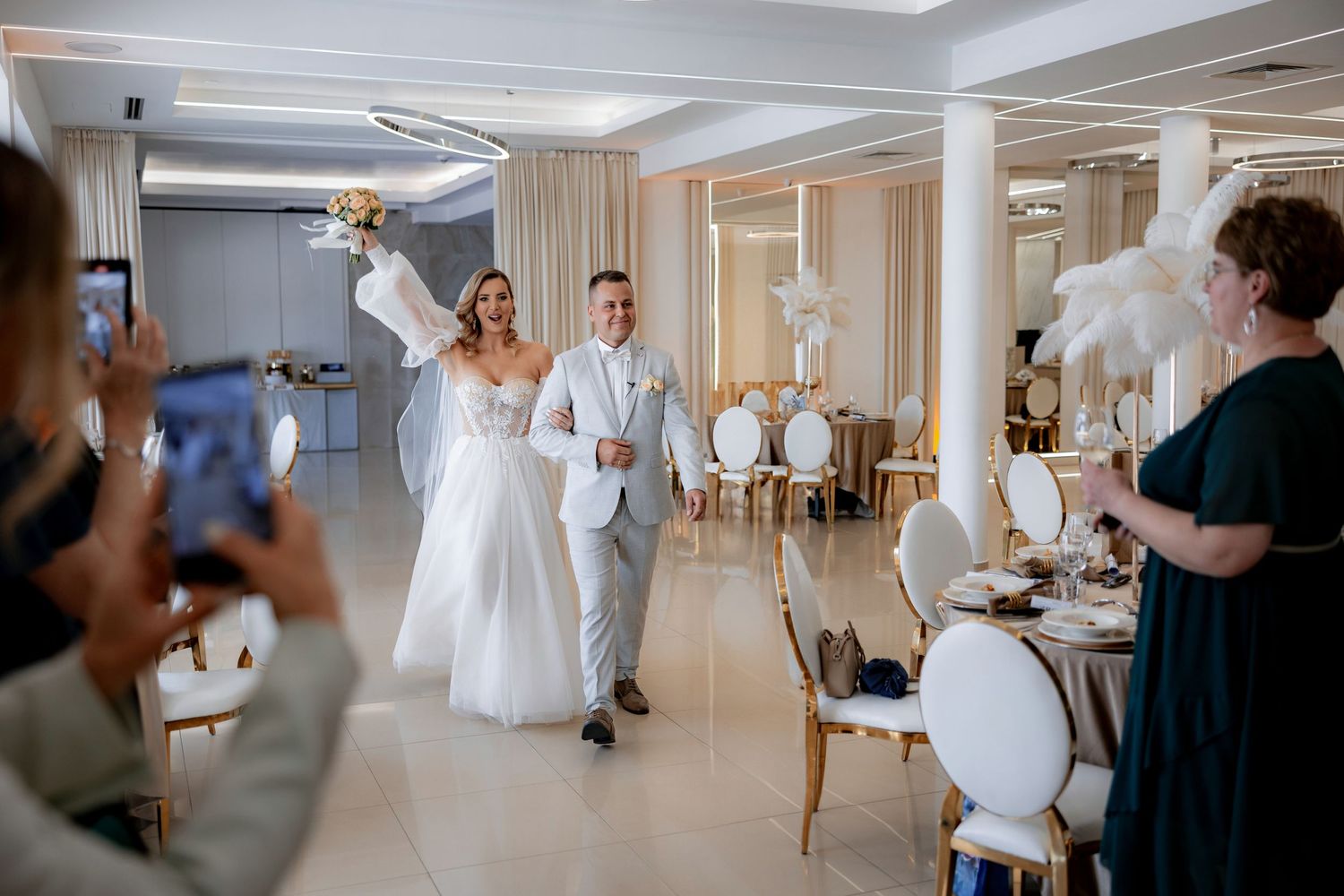Wedding celebration entrance with couple walking through venue decorated with white feathers.
