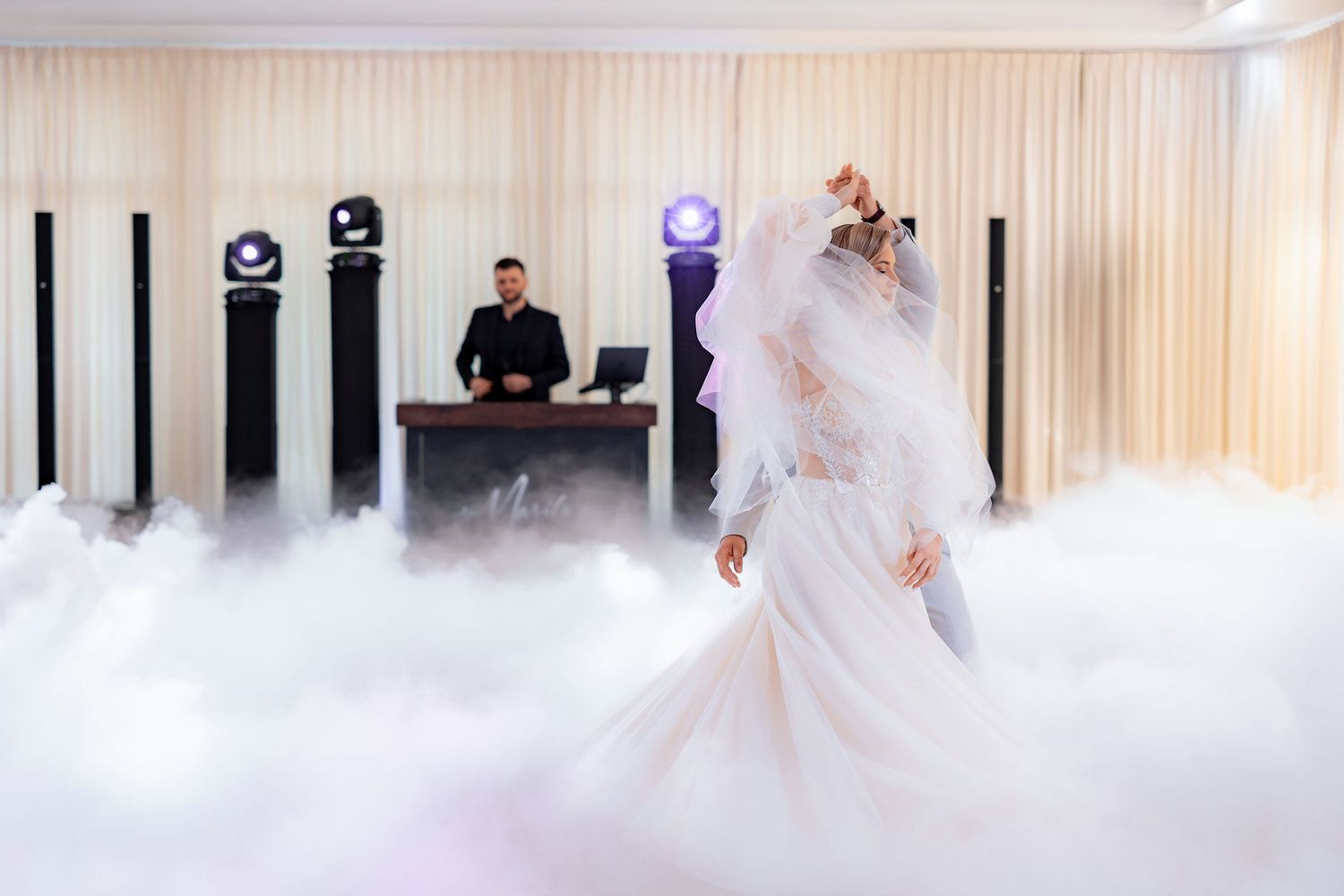 A bride dances in a cloud of fog during the first dance at an elegant wedding reception.