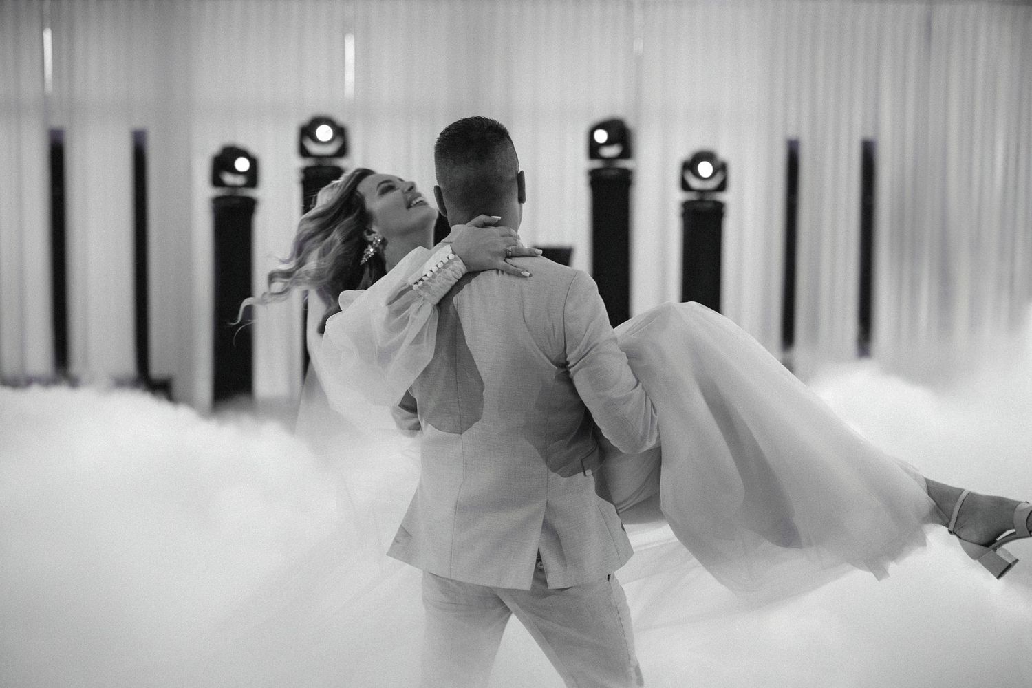 A couple dancing at their wedding reception in black and white, surrounded by fog on the dance floor.
