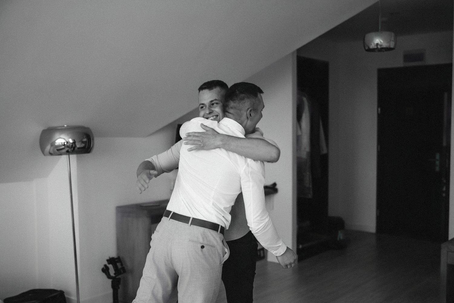 Black and white photograph of an emotional embrace during wedding preparations.