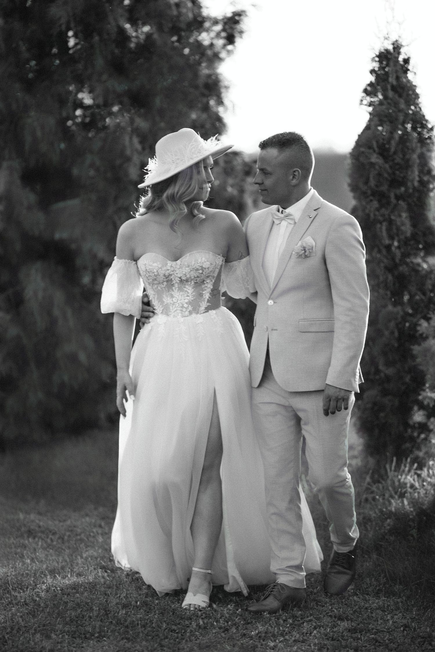 Black and white photo of couple in wedding attire standing together outdoors.