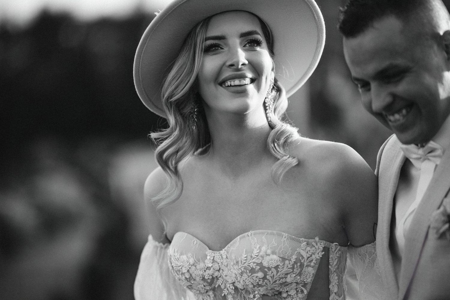 Black and white candid of joyful wedding couple during outdoor celebration.