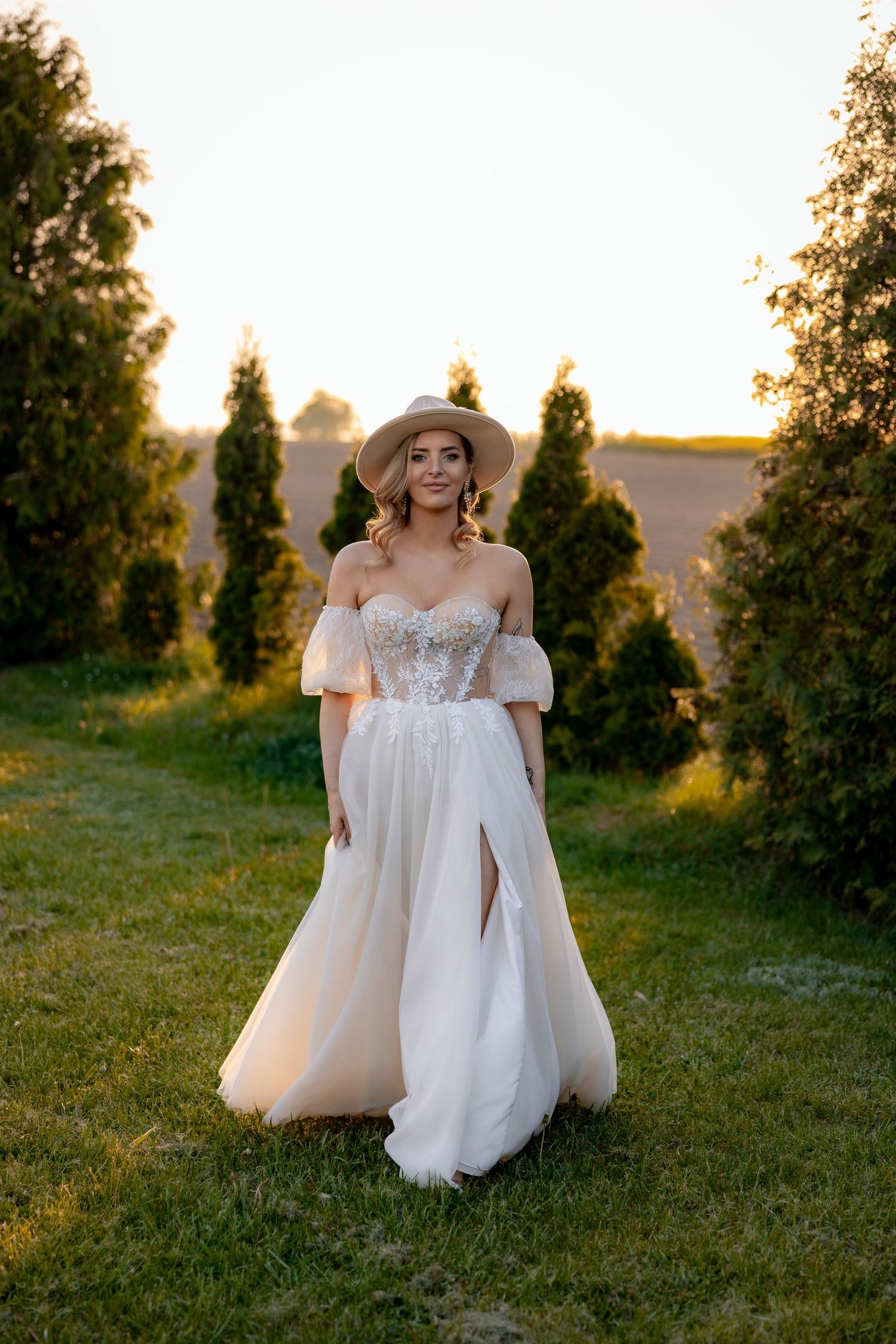 Ethereal bridal portrait in a flowing white gown against a sunset garden backdrop.