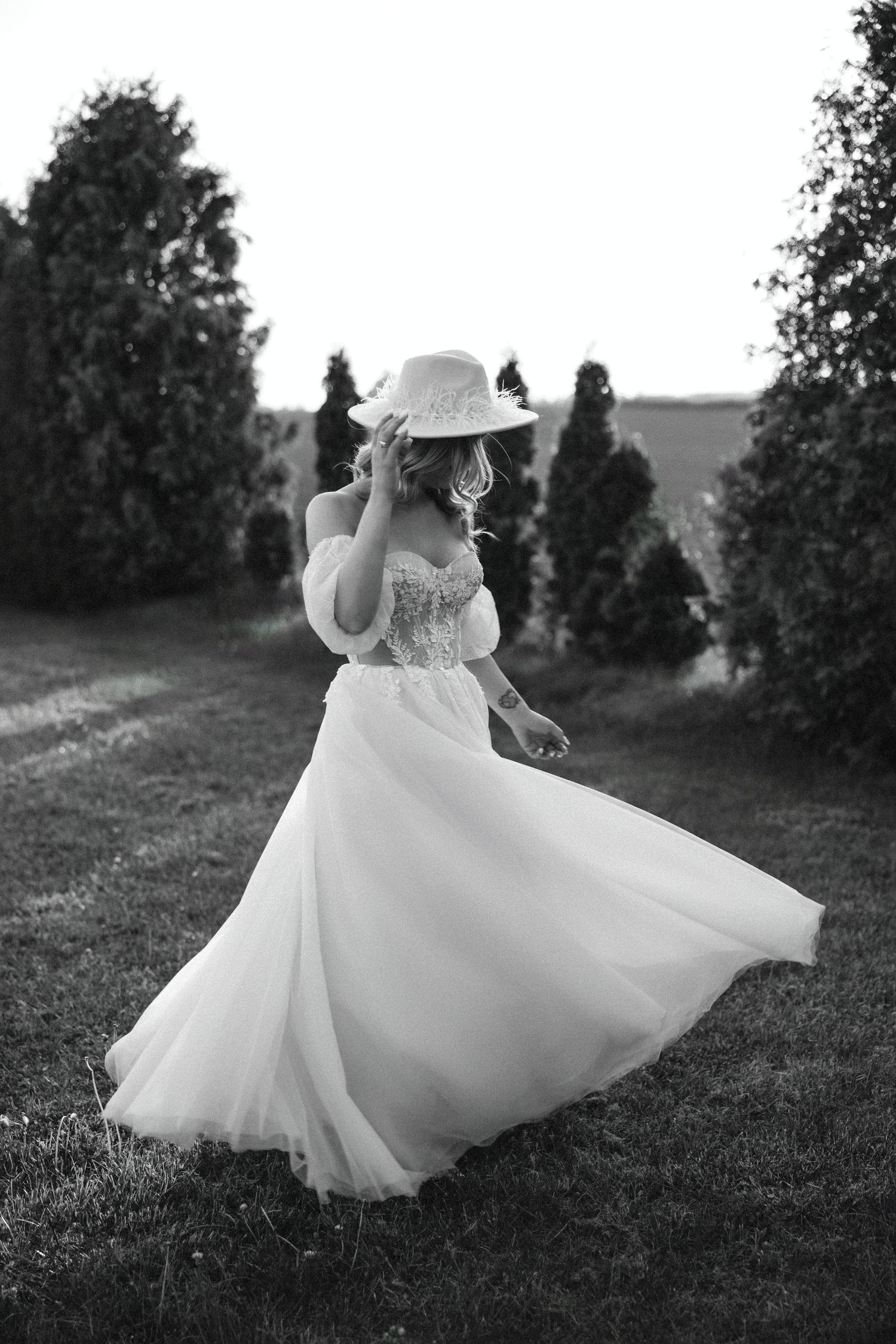 Black and white wedding photo capturing movement of a flowing dress among garden trees.