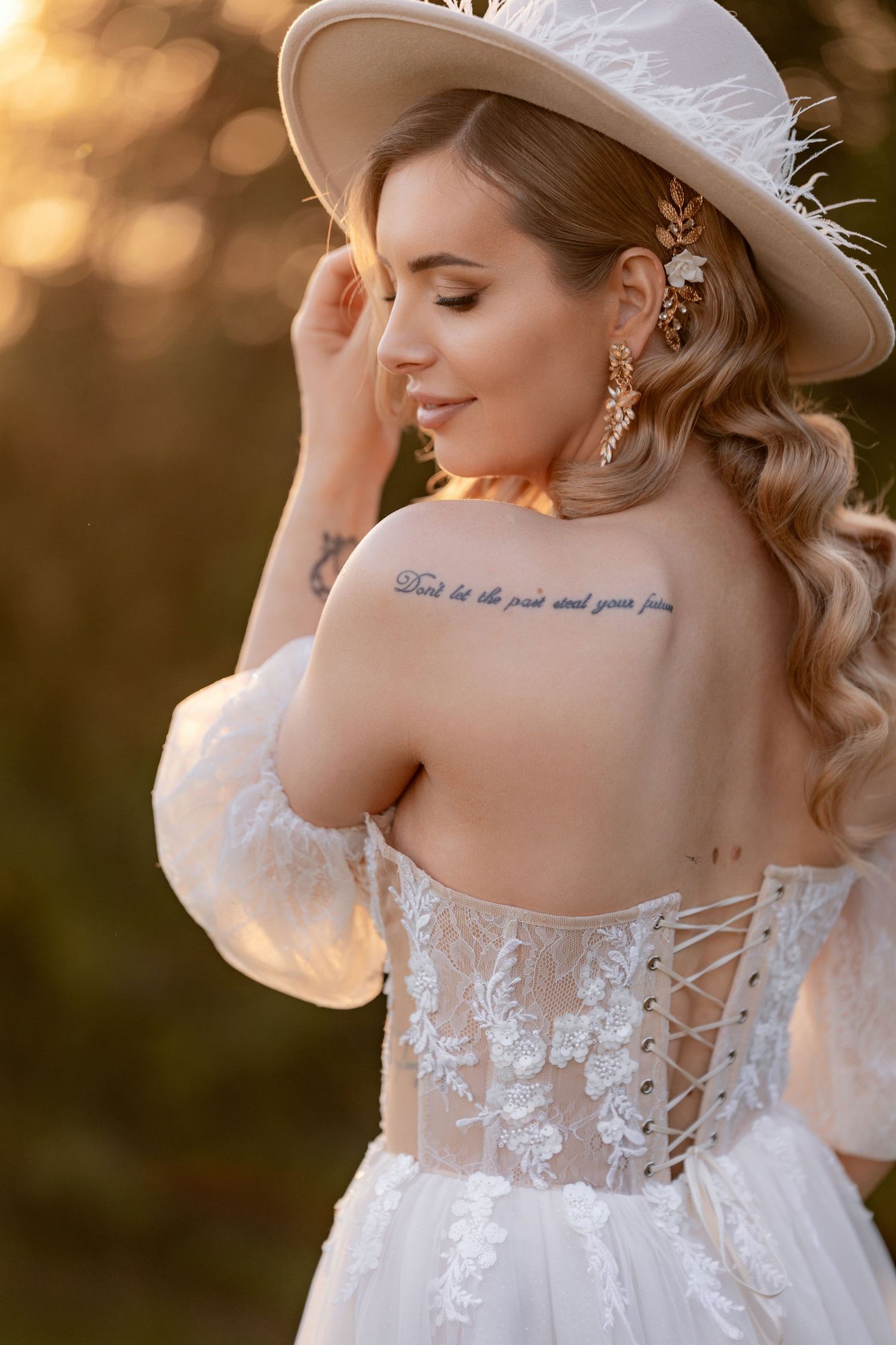 A close-up view of a wedding dress showing intricate lace details and corset back in golden light.