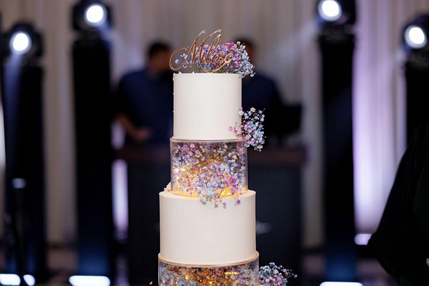Elegant white tiered wedding cake decorated with colorful sprinkles and metallic accents.