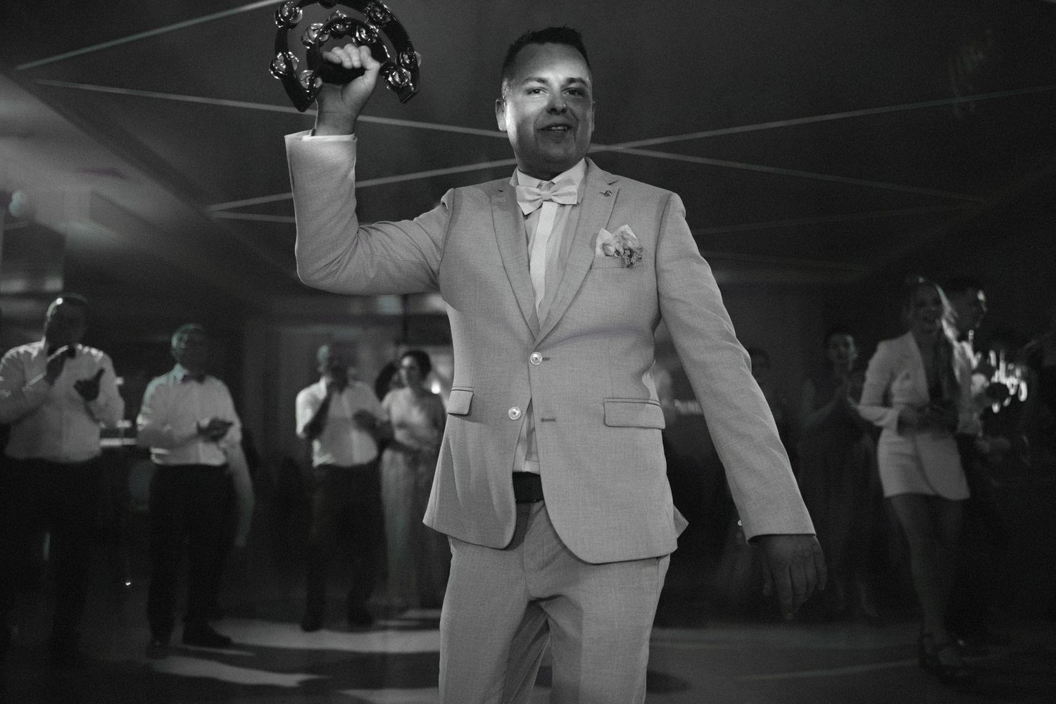 Wedding guest in light gray suit dancing enthusiastically at reception.