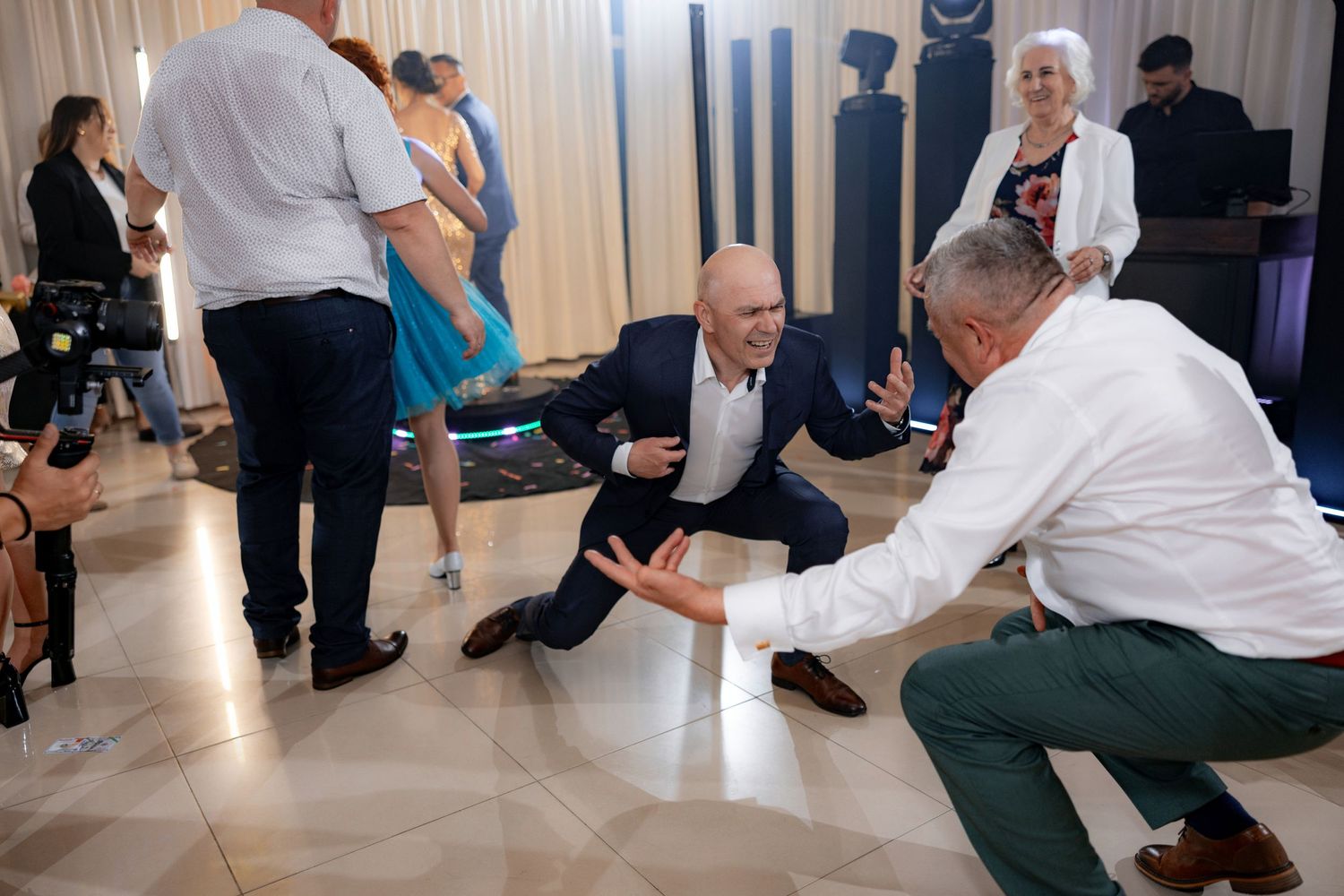 Wedding guests engaged in lively conversation on dance floor during reception.