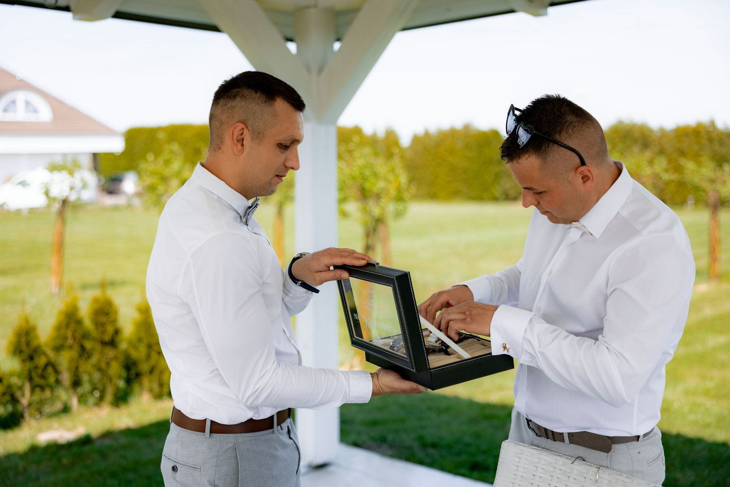 Two people in white shirts examining items in a display box outdoors.