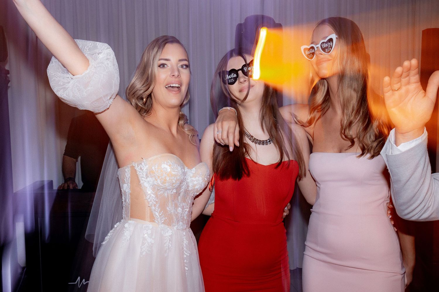 Wedding party celebrating on dance floor with vibrant orange lighting effects.