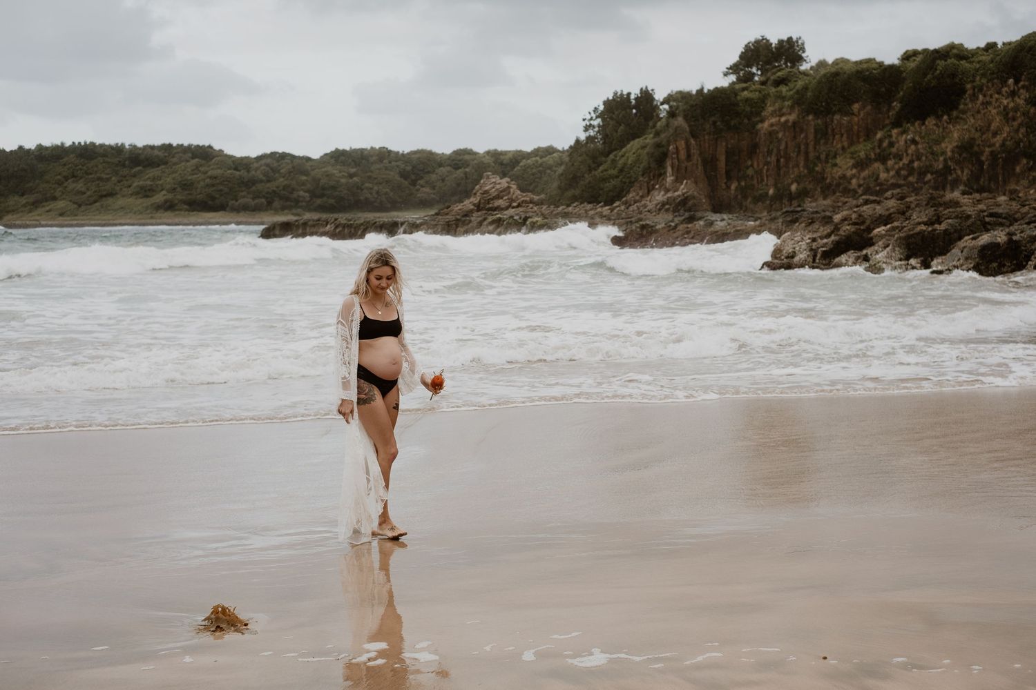 A silhouette walking along a dramatic rocky coastline beach.