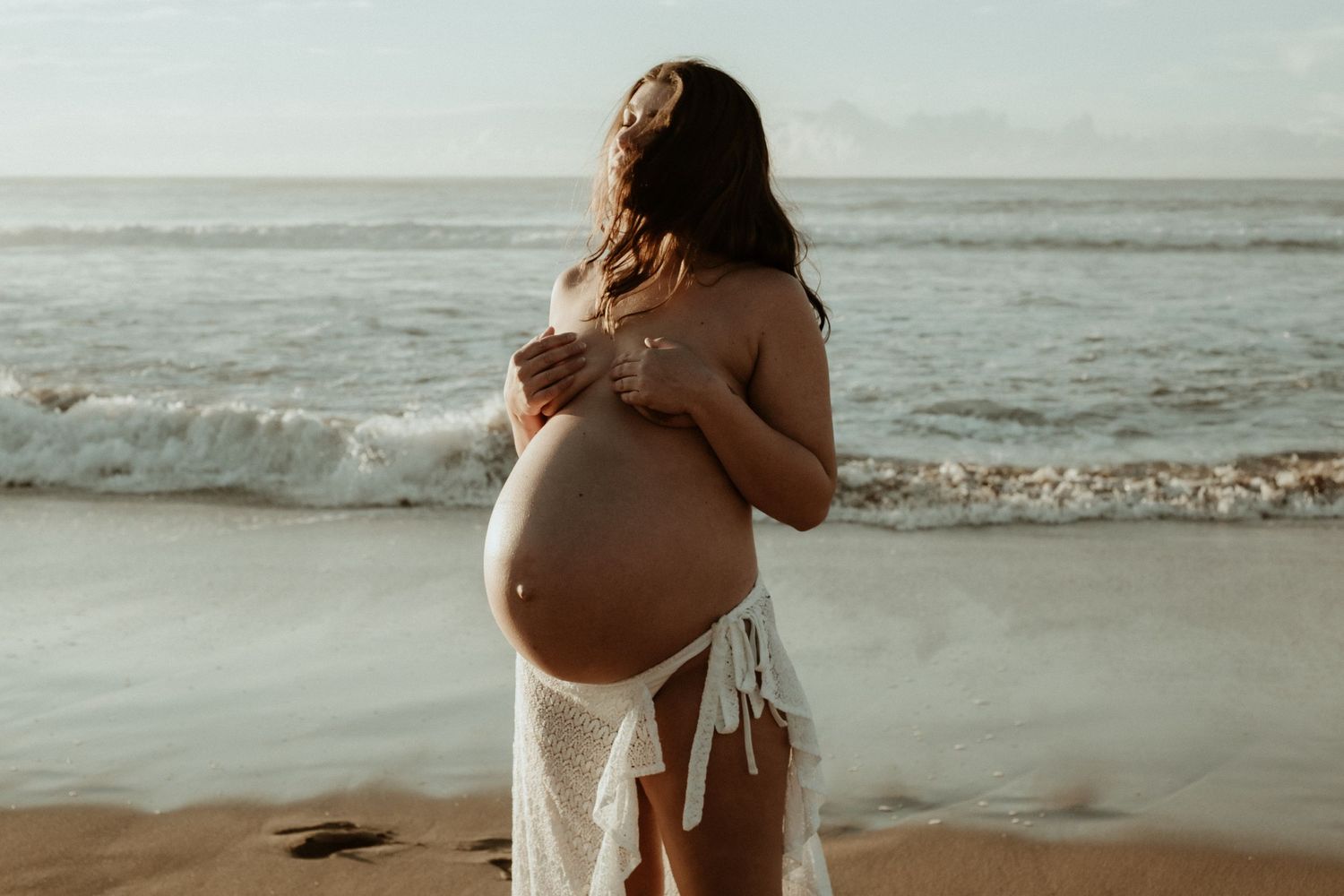 Ethereal beach maternity photos with waves and golden light.