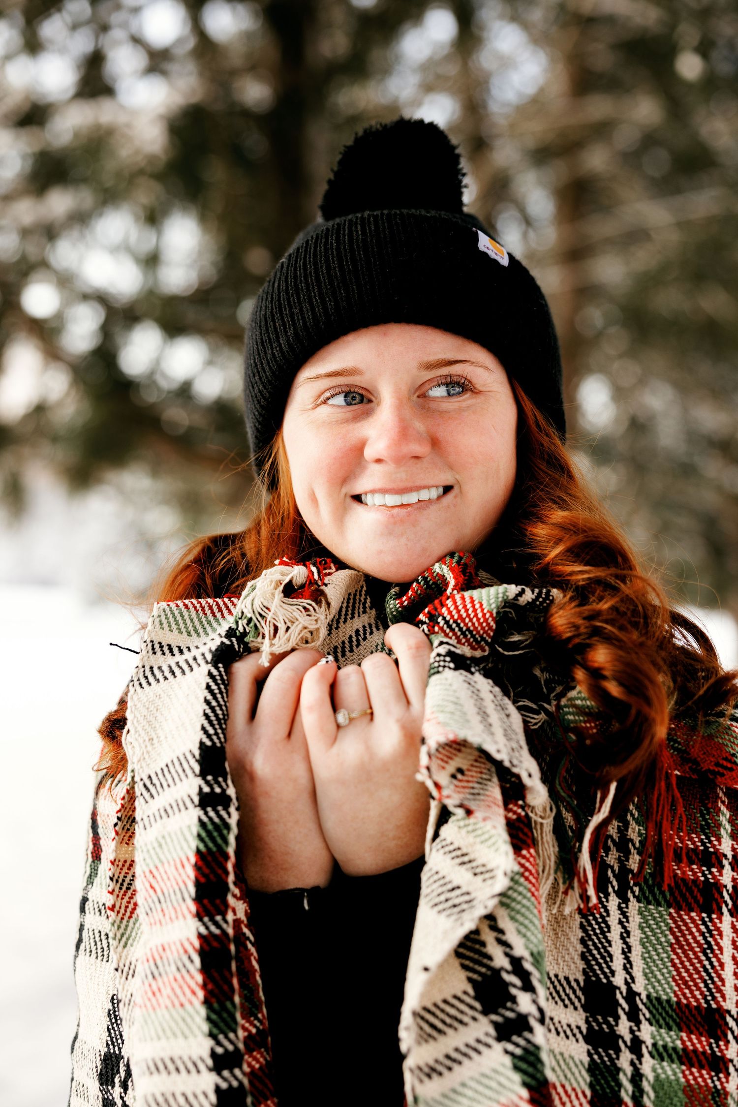 Winter portrait of person in plaid blanket and black beanie hat.