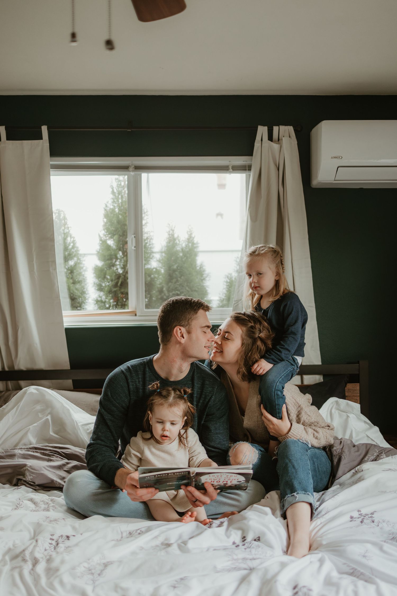 A tender family moment shared on a cozy bed in a sunlit bedroom.