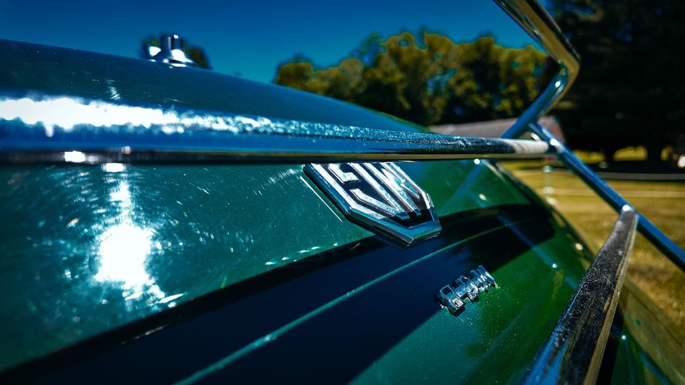 Close-up details of a British racing green Jaguar E-Type's exterior chrome and bodywork.