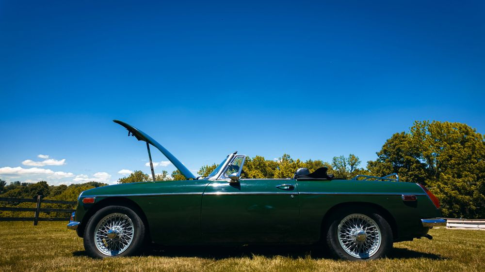 Panoramic shots of a green Jaguar E-Type convertible in a scenic outdoor setting.