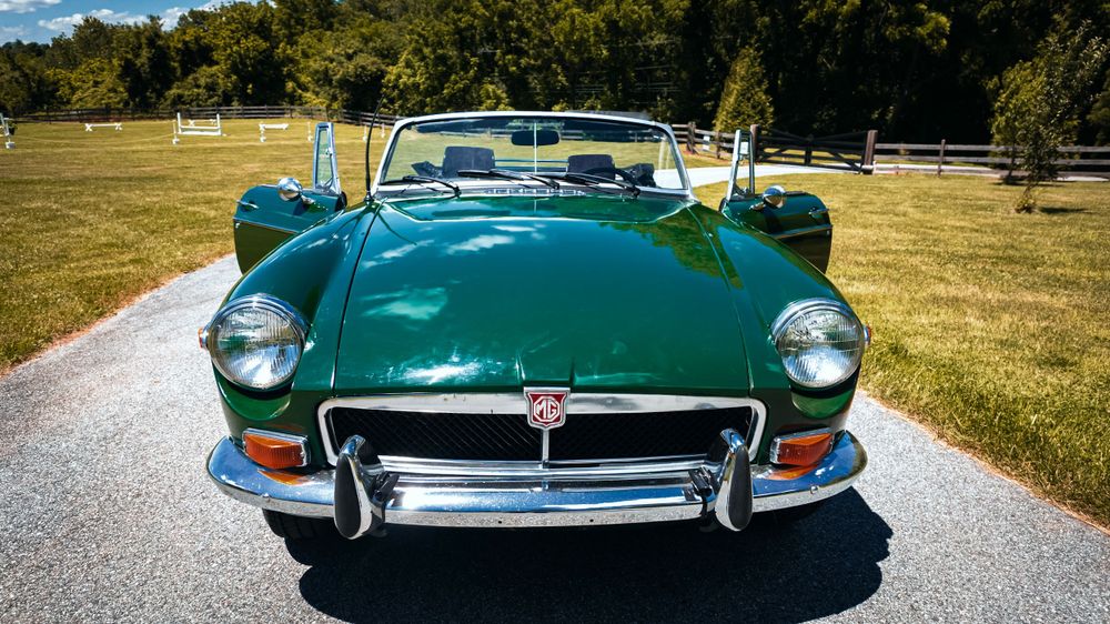 Front grille and headlight details of a classic green Jaguar E-Type sports car.